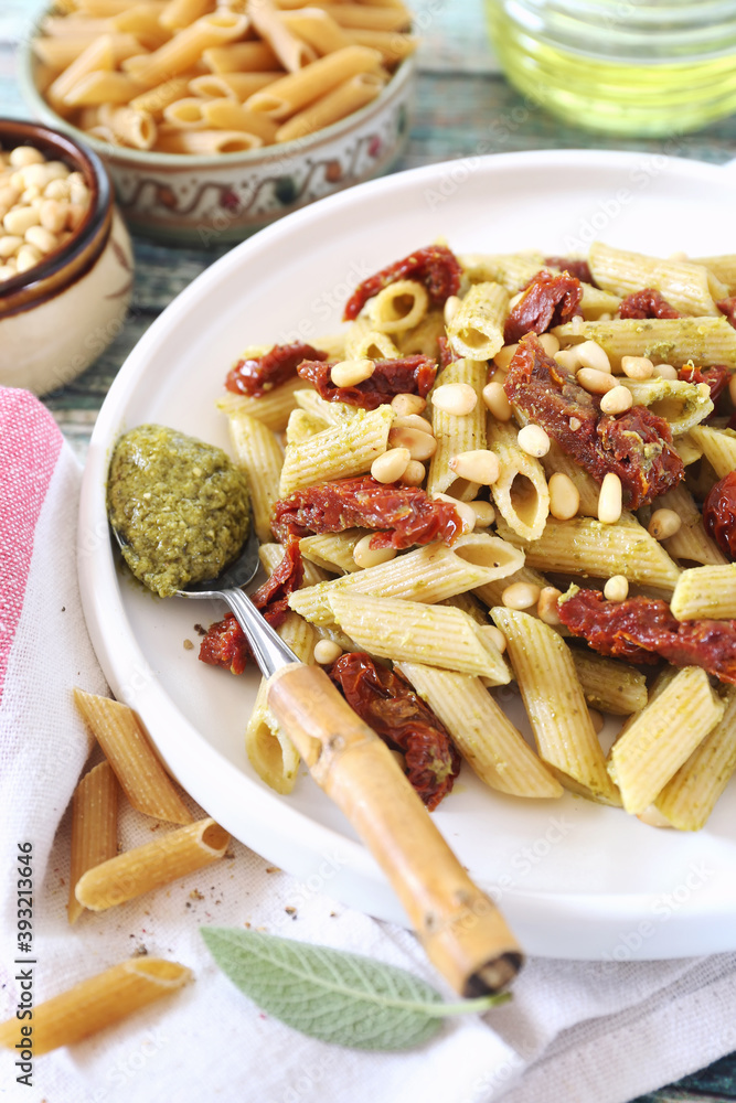 Whole wheat penne pasta with pesto sauce and sun dried tomatoes, pine nut dressing Whole wheat penne pasta with pesto sauce and sun dried tomatoes, pine nut dressing