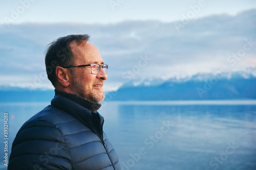 Happy smiling mature man admiring winter lake