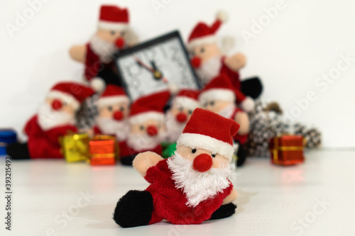 funny toy santa claus on blurred background of table clock and other santa claus