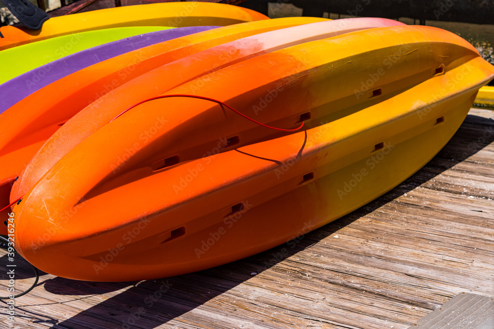 Closeup View of Many Colorful Kayaks Drying in Sun on a Pier. Colored Canoes are Waiting for Tourists. Selective focus. Closeup View of Many Colorful Kayaks Drying in Sun on a Pier. Colored Canoes are Waiting for Tourists. Selective focus.