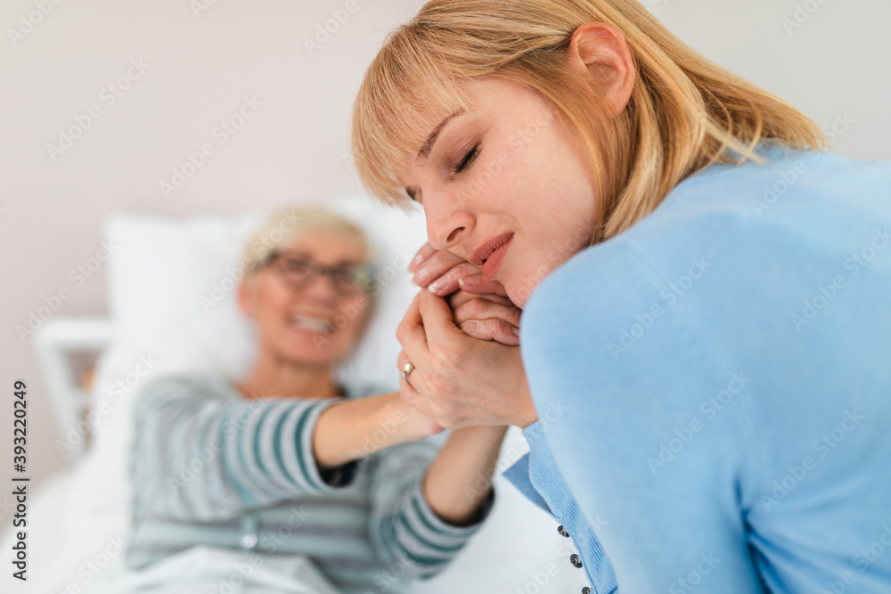 Beautiful middle age woman spending some time with her mother in hospital or nursing center. Senior woman lying in bed. Beautiful middle age woman spending some time with her mother in hospital or nursing center. Senior woman lying in bed.