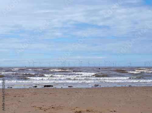 the beach at blundell flats in southport with waves breaking on the beach and the wind turbines at burbo bank visible in the distance © Philip J Openshaw 