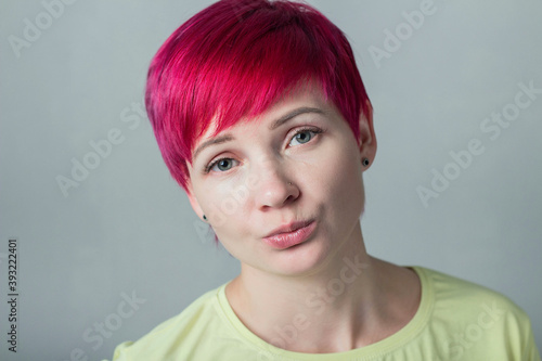 Portrait of a sad woman with short dark pink hair