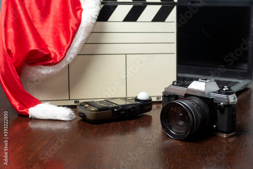 notbook next to a clapperboard. camera and handheld photometer, cell phone on wood in zenith plane and Christmas hat photo