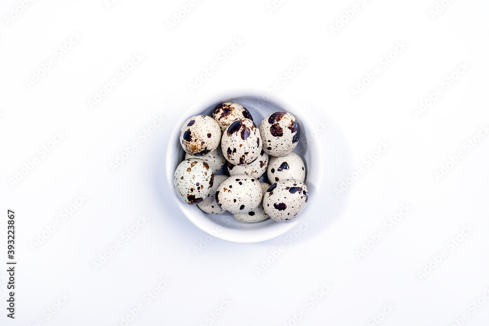 Quail eggs in white ceramic bowl isolated on white background. Top view. Detailed closeup of spotted quail eggs Quail eggs in white ceramic bowl isolated on white background. Top view. Detailed closeup of spotted quail eggs