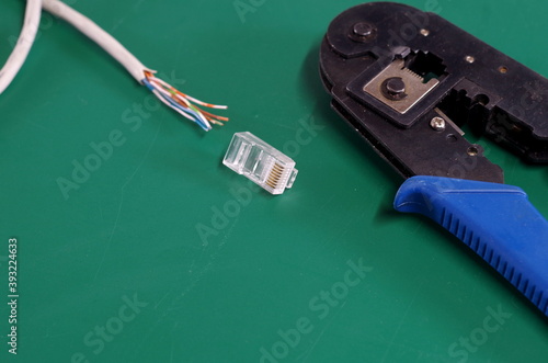 cat5 network cable with exposed wires and rj45 plug with crimping tool