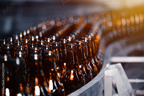 Glass beer bottles of brown color on the conveyor line of beer bottling close up