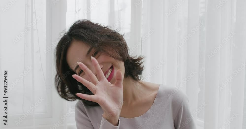 Young Asian woman in a gray T-shirt standing in front of a white curtain talking to camera pretty cute lovely lady chatting speak to webcam indoor POV view of happy girlfriend talk Young Asian woman in a gray T-shirt standing in front of a white curtain talking to camera pretty cute lovely lady chatting speak to webcam indoor POV view of happy girlfriend talk