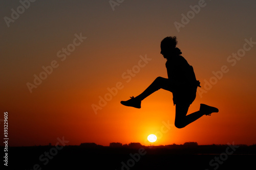 silueta de chico a contraluz saltando el sol con los pelos al viento
