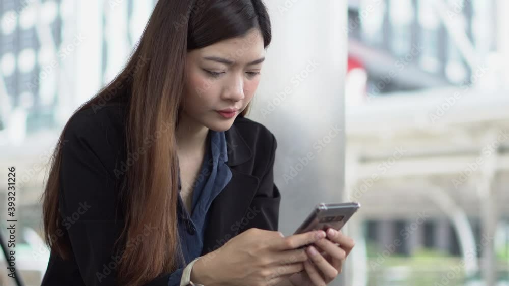 Asian Thai girl using mobile phone in business market.Person front view of Young Woman holding smartphone via internet to sending message and searching on digital device.Technology Concept. Asian Thai girl using mobile phone in business market.Person front view of Young Woman holding smartphone via internet to sending message and searching on digital device.Technology Concept.