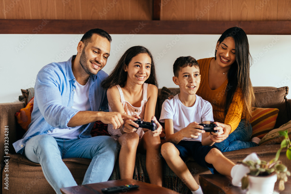 Latin family enjoying the day together at home playing video games on the couch Latin family enjoying the day together at home playing video games on the couch