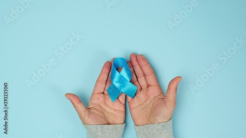 Wallpaper Mural female hand holds blue silk ribbon in the shape of a loop on a blue background, symbol of the fight and treatment of prostate cancer Torontodigital.ca