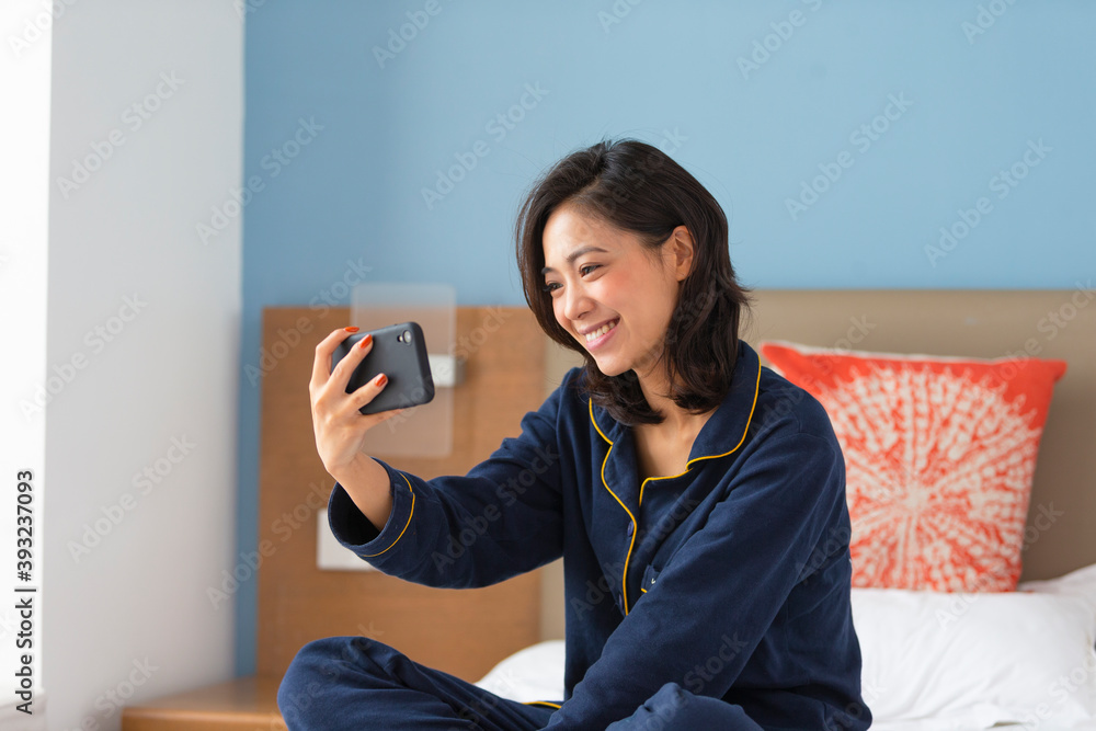 happy young asian woman sitting in bed video call on mobile phone indoor at home happy young asian woman sitting in bed video call on mobile phone indoor at home