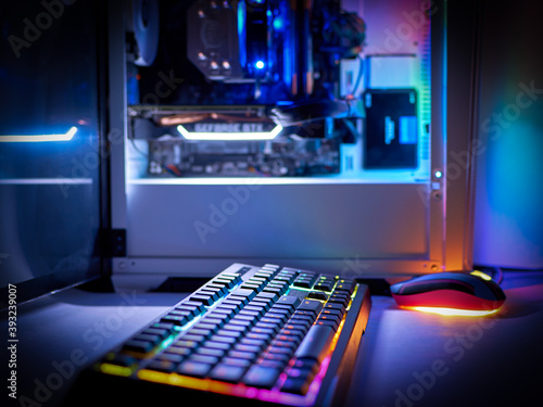 Fototapeta Naklejka Na Ścianę i Meble -  Desktop gaming PC and backlit keyboard. Components of the computer. PC case with RGB light, blurred background.