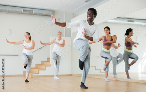 Portrait of dancing African-American practicing vigorous swing during group training in dance studio.