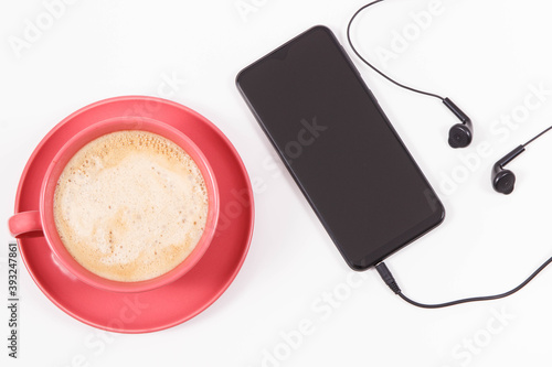 Mobile phone with connected headphones and coffee with milk. Relaxation time with music. White background