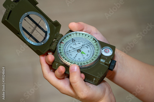Children's hands holding a compass. A little boy holds a green compass in his hands. Learn orienteering. Childhood curiosity and adventure