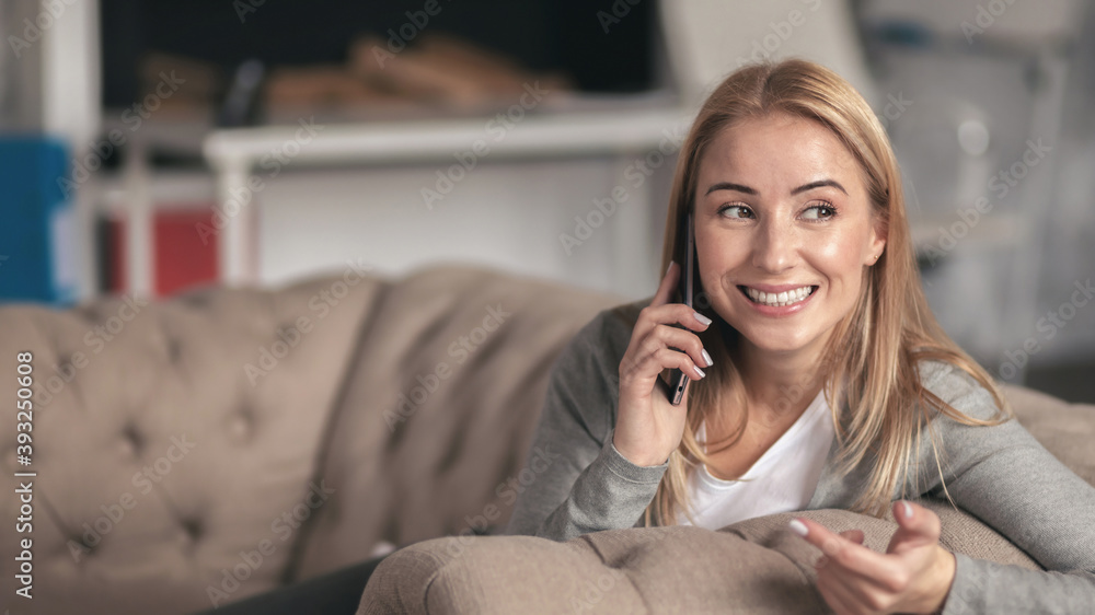 Beautiful young woman talking on the phone while sitting at home on the sofa Beautiful young woman talking on the phone while sitting at home on the sofa