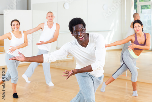 Cheerful african american man practicing vigorous lindy hop movements in group dance class.