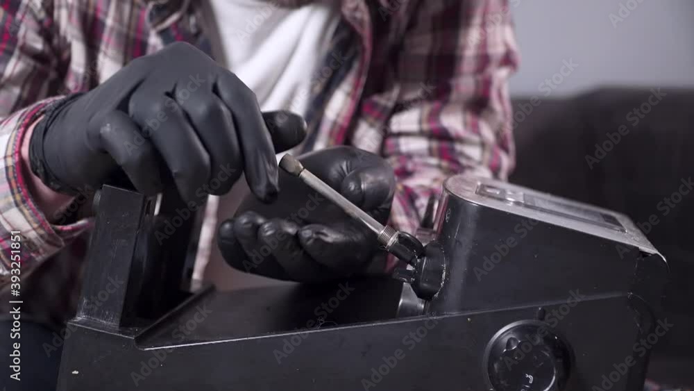 A young man is trying to fix his own kitchen appliances at home, a coffee maker. Caucasian male repairs a coffee machine with a screwdriver dressed in a plaid shirt and safety glasses and gloves A young man is trying to fix his own kitchen appliances at home, a coffee maker. Caucasian male repairs a coffee machine with a screwdriver dressed in a plaid shirt and safety glasses and gloves