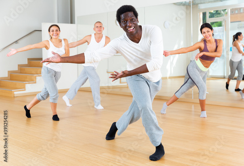 Portrait of emotional young adult man doing exercises during group class in dance center
