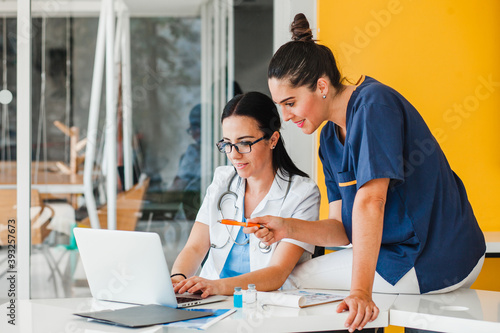 hispanic women doctor and nurse with computer in consulting room in Mexico