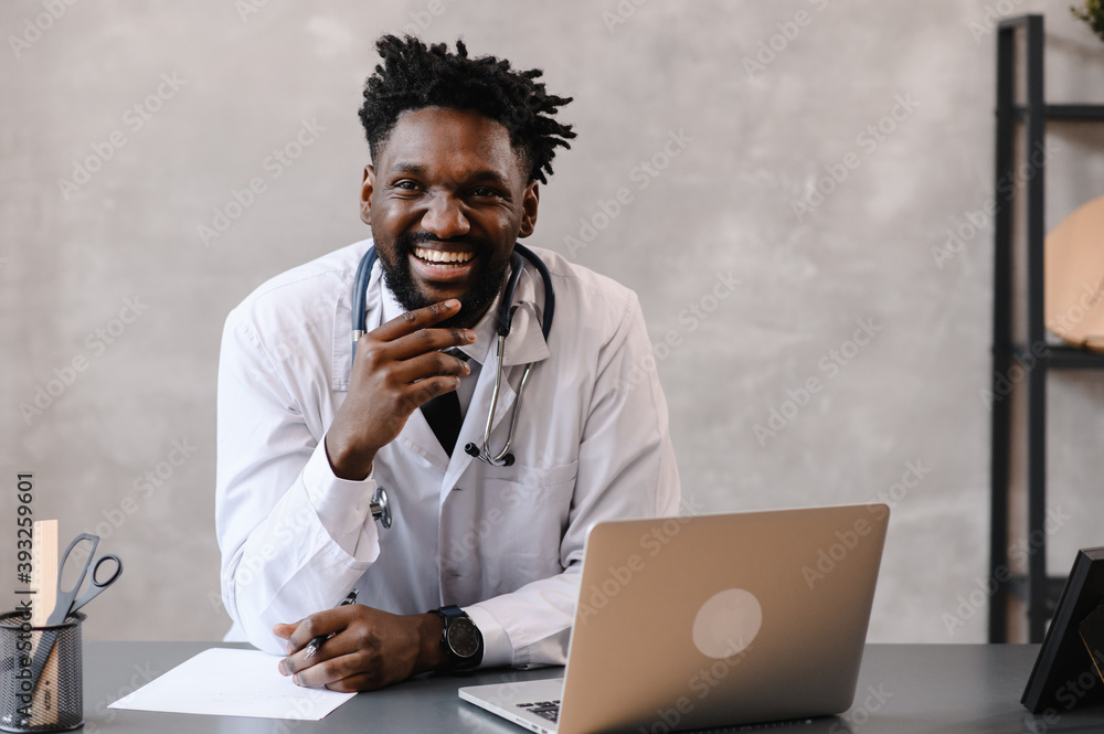 Handsome contented African American doctor working on a laptop. telemedicine Handsome contented African American doctor working on a laptop. telemedicine