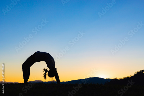 Silhouette Young woman is practicing yoga at mountain sunset © AungMyo