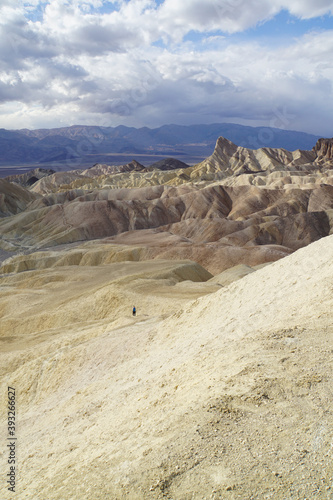A hiker in the distance, exploring the badlands terrain, as seen from Zabriskie Point in Death Valley National Park