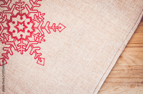 Fotografia, Obraz Overhead shot of a burlap cloth decorated with a sewed red snowflake