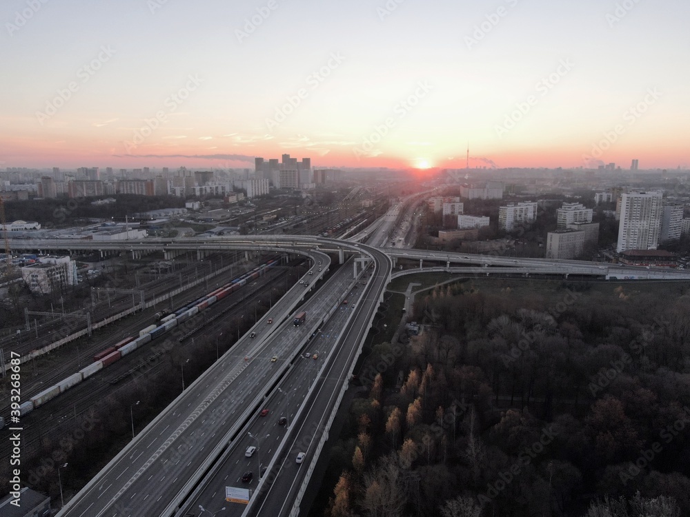 Fototapeta premium Aerial view panorama of multi-level transport interchange in the center of the big city at dawn. Beautiful panoramic landscape infrastructure of modern city from great height