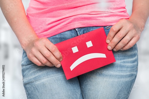 Woman with incontinence problem with sad smiley on paper photo