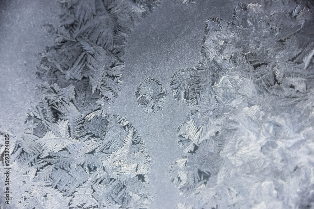 Fototapeta premium Texture of blue frost on a glass window. Frosty cold weather. White ice patterns texture close-up. New year and Christmas background