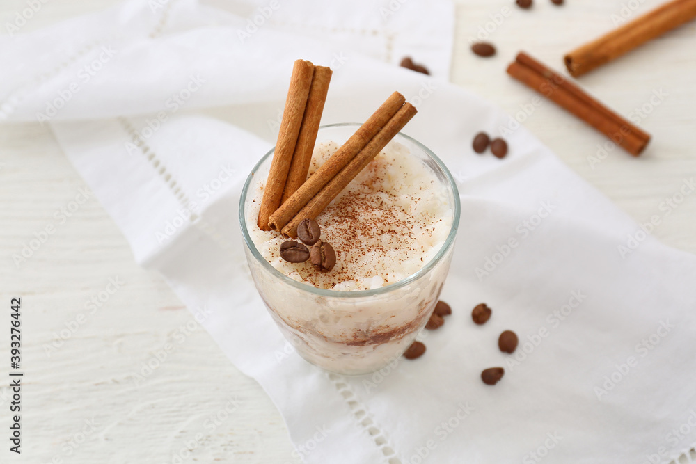 Glass of tasty rice pudding with cinnamon on light table Glass of tasty rice pudding with cinnamon on light table