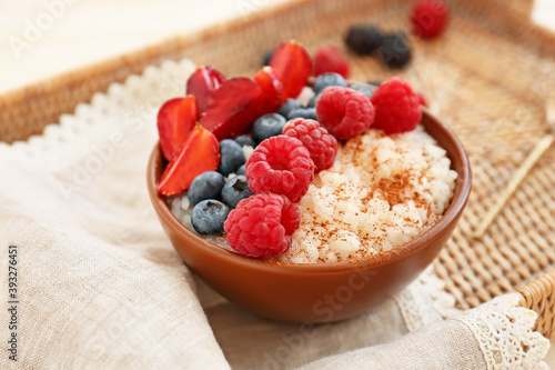 Fotografie, Obraz Bowl of tasty rice pudding with berries on wicker tray
