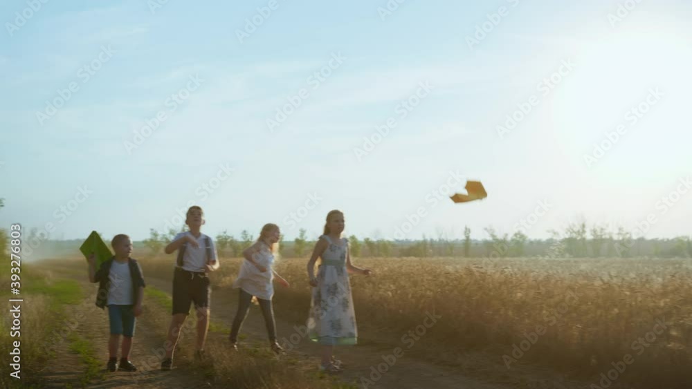 best friends, boys and girls on dusty country road launch paper planes into the air near the golden wheat field against the blue sky best friends, boys and girls on dusty country road launch paper planes into the air near the golden wheat field against the blue sky