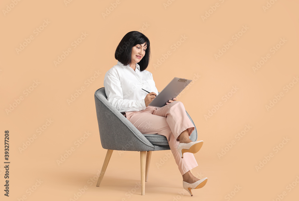Portrait of female psychologist sitting in armchair on color background Portrait of female psychologist sitting in armchair on color background