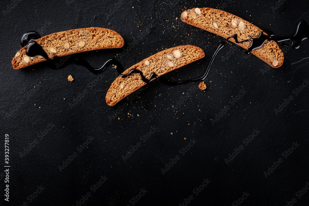 Cantucci. Traditional Italian almond cookies, shot from above on a black background with chocolate and a place for text Cantucci. Traditional Italian almond cookies, shot from above on a black background with chocolate and a place for text