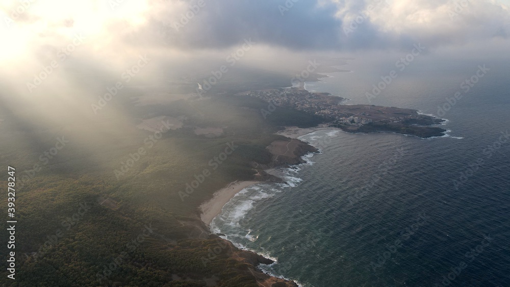 Sun rays over a coastal forest and small town