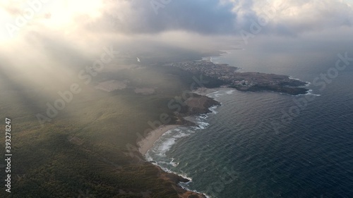 Sun rays over a coastal forest and small town