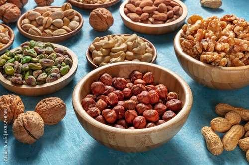 Many different nuts in wooden bowls on a vibrant blue background