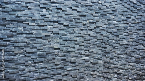 Natural gray brick used as a wall. The bricks are arranged alternately horizontally, creating an overlap of color and shadow.