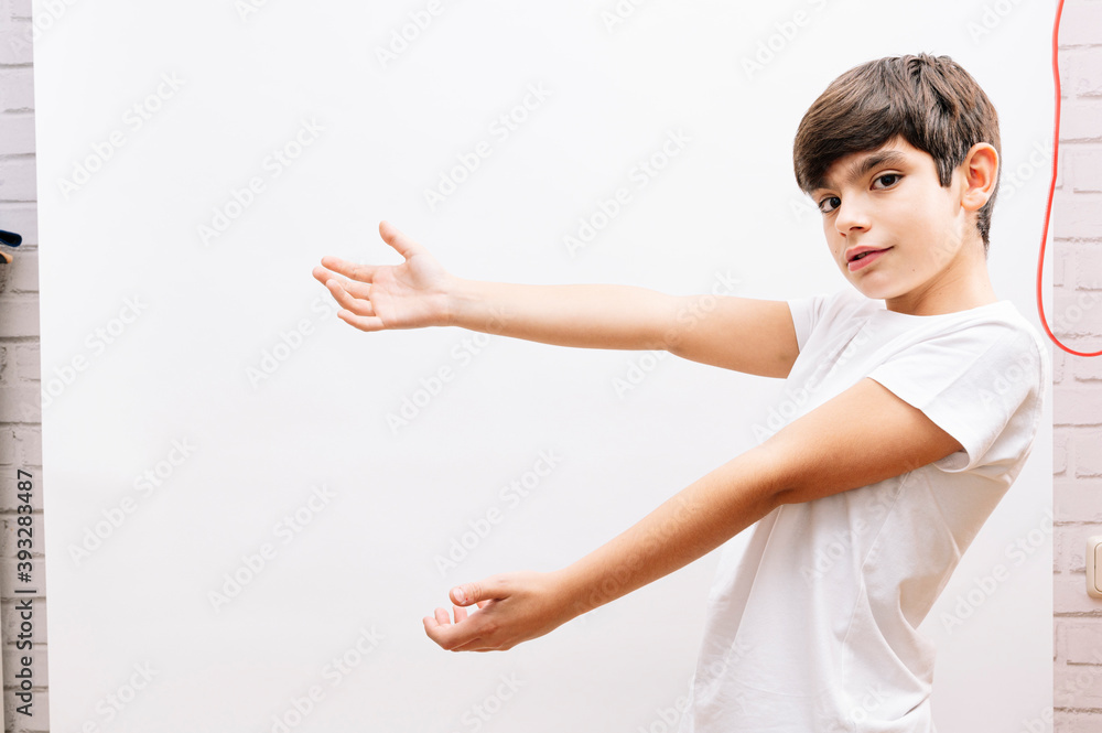 Little boy hispanic kid wearing white t-shirt inviting to enter smiling natural with open hand Little boy hispanic kid wearing white t-shirt inviting to enter smiling natural with open hand