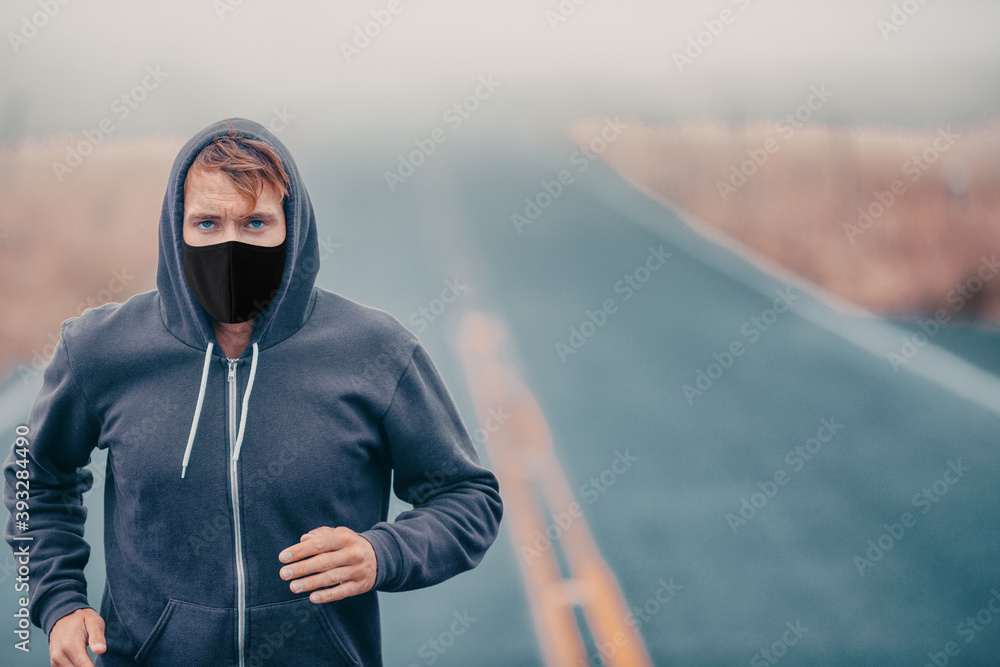 Fototapeta premium Sports mask endurance athlete runner running outside on road training while wearing facial covering in cold weather winter fog. Male jogger man jogging.