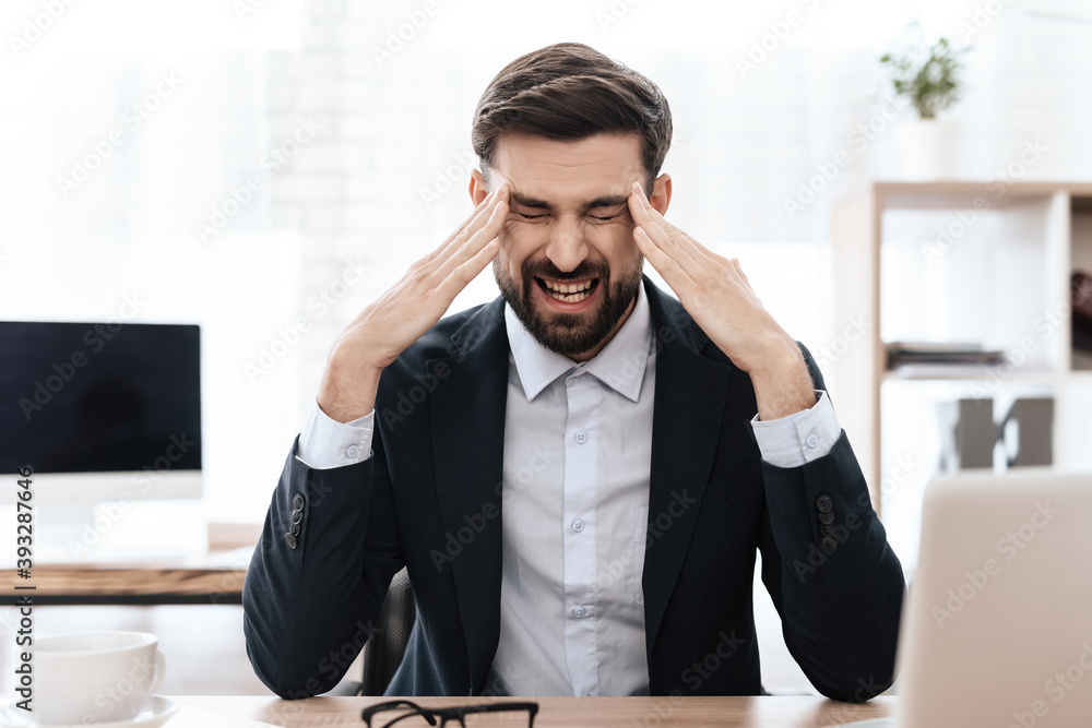 Fototapeta premium A man in a suit sits and feels pain in his head.