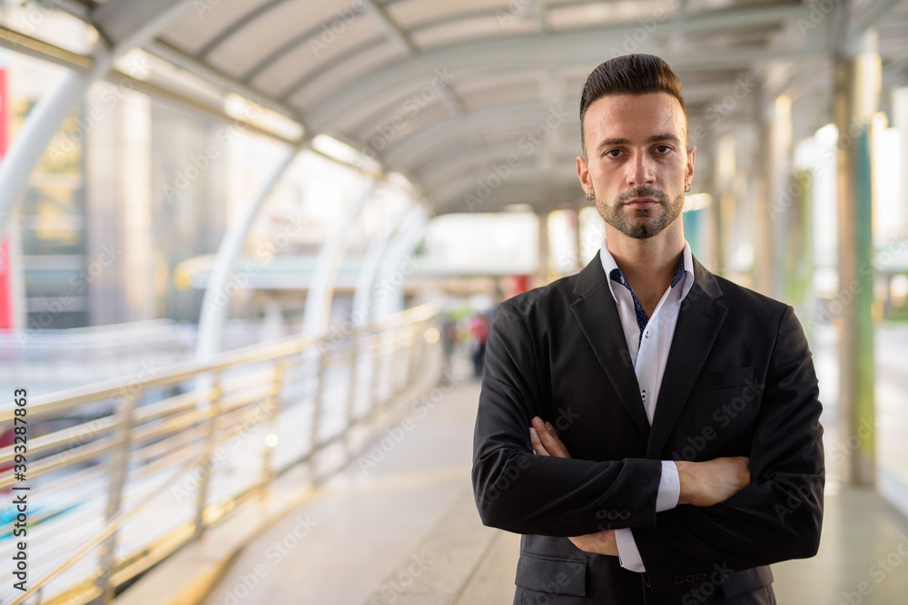 Confident businessman outdoors in city with arms crossed