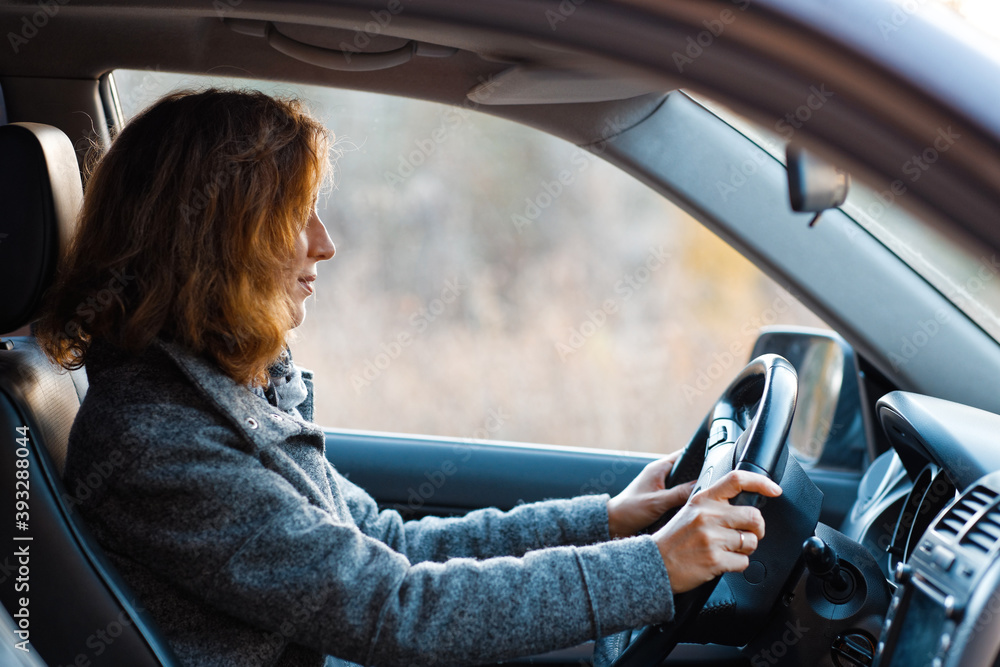 Naklejka premium Portrait of a redhead woman driving a car and looking straight ahead.