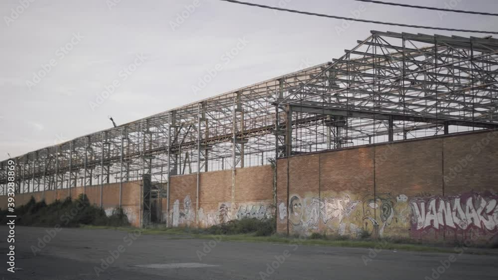 Abandoned warehouse - Panoramic shot from the outside with murals on the wall at sunset Abandoned warehouse - Panoramic shot from the outside with murals on the wall at sunset