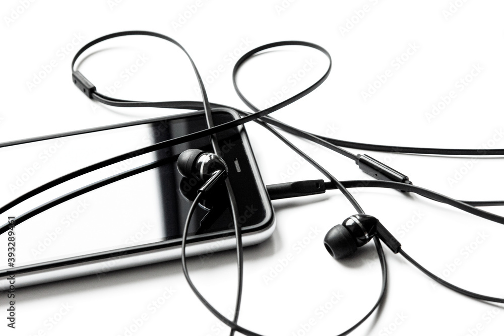 Headphones are connected to the smartphone on a white background. Ear plugs for listening music and sounds on portable devices. Earflaps for a mobile phone. Headset from two earpieces. Playing music. Headphones are connected to the smartphone on a white background. Ear plugs for listening music and sounds on portable devices. Earflaps for a mobile phone. Headset from two earpieces. Playing music.