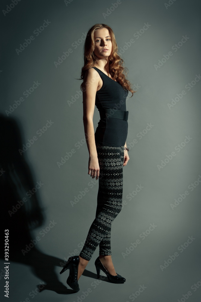 beautiful slender blonde girl in black tights and a tank top on a gray background beautiful slender blonde girl in black tights and a tank top on a gray background